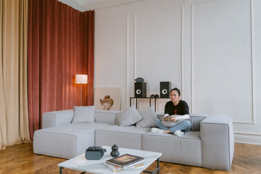 A girl playing with playstation on a gray couch